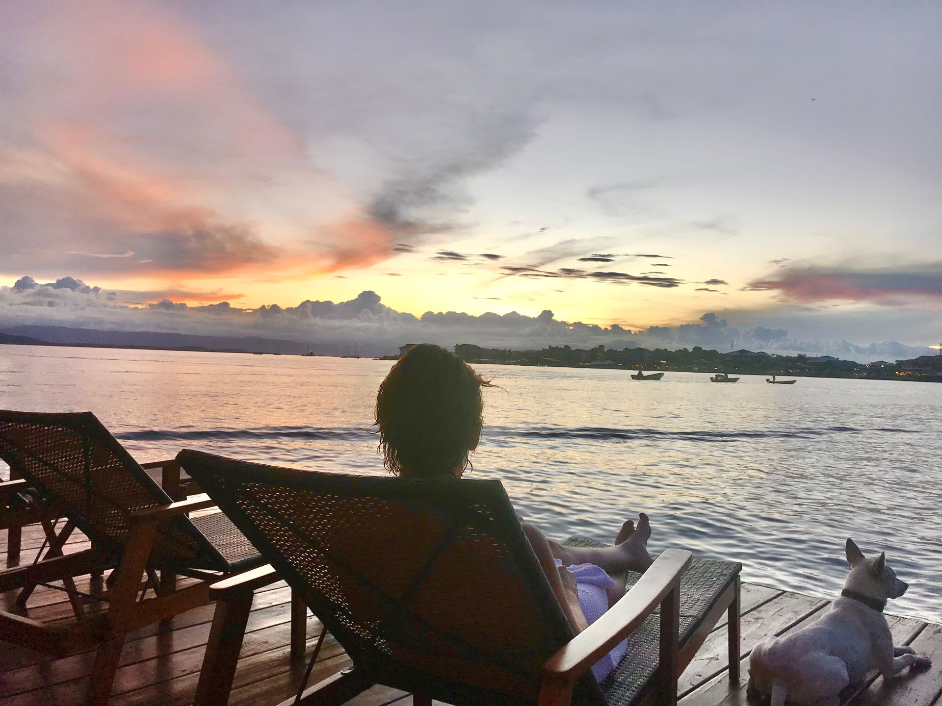 A person is sitting in a chair on a dock looking at the ocean.