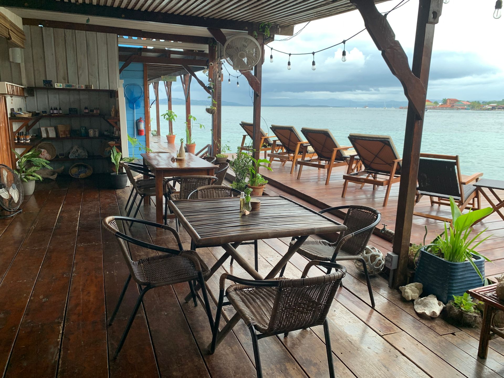 A wooden deck with tables and chairs overlooking the ocean