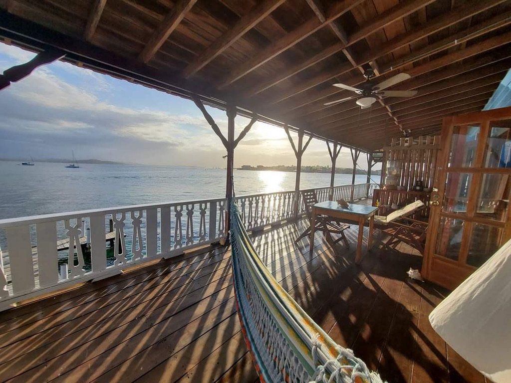 A wooden deck with a hammock and chairs overlooking the ocean.