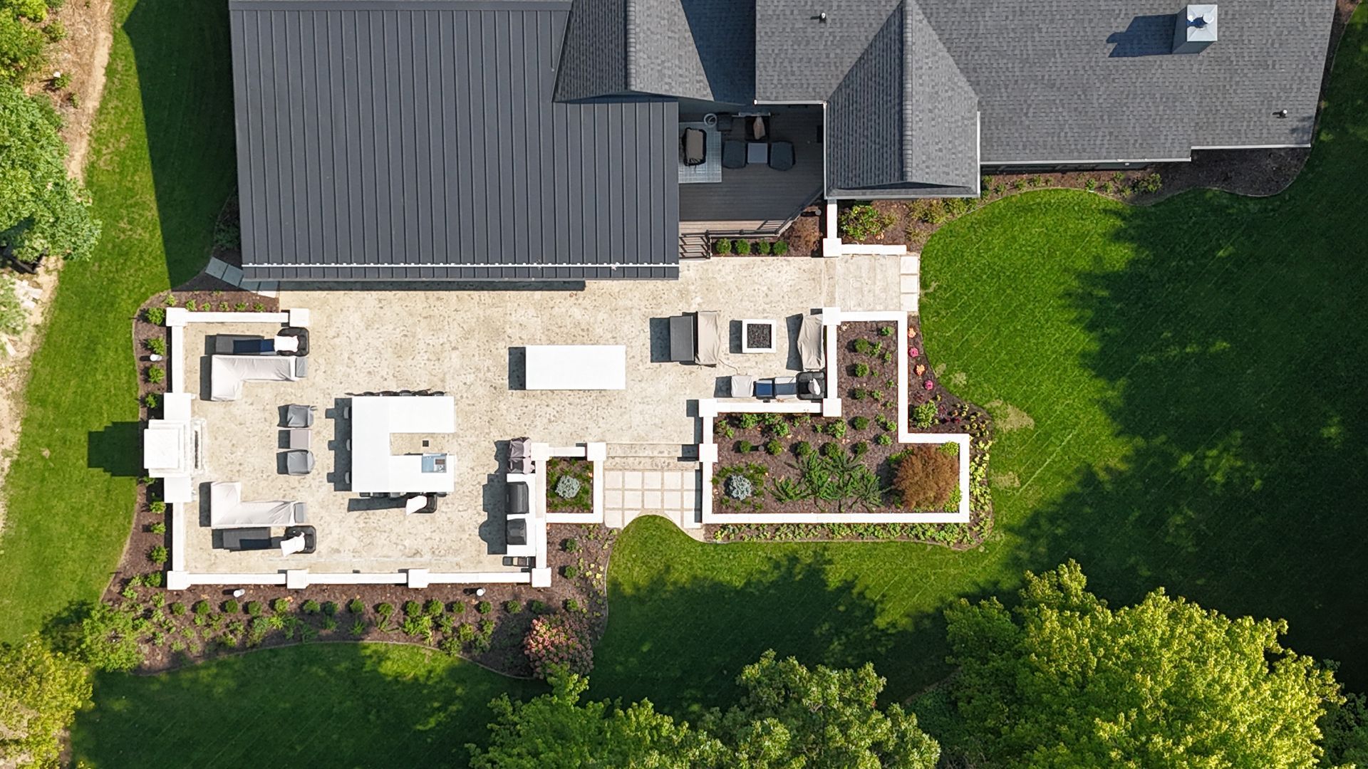 Overhead view of a house with a stone patio, outdoor seating, and a landscaped garden.