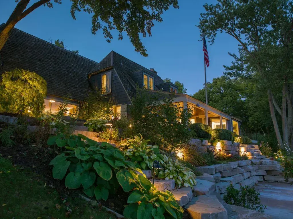 Nighttime view of a house with garden lighting and American flag.