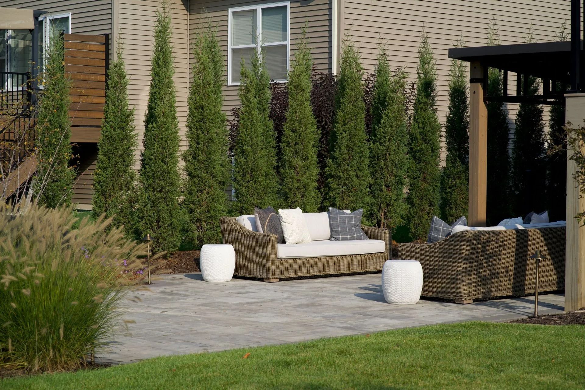 Patio with gray stone pavers, outdoor seating, and tall green trees.