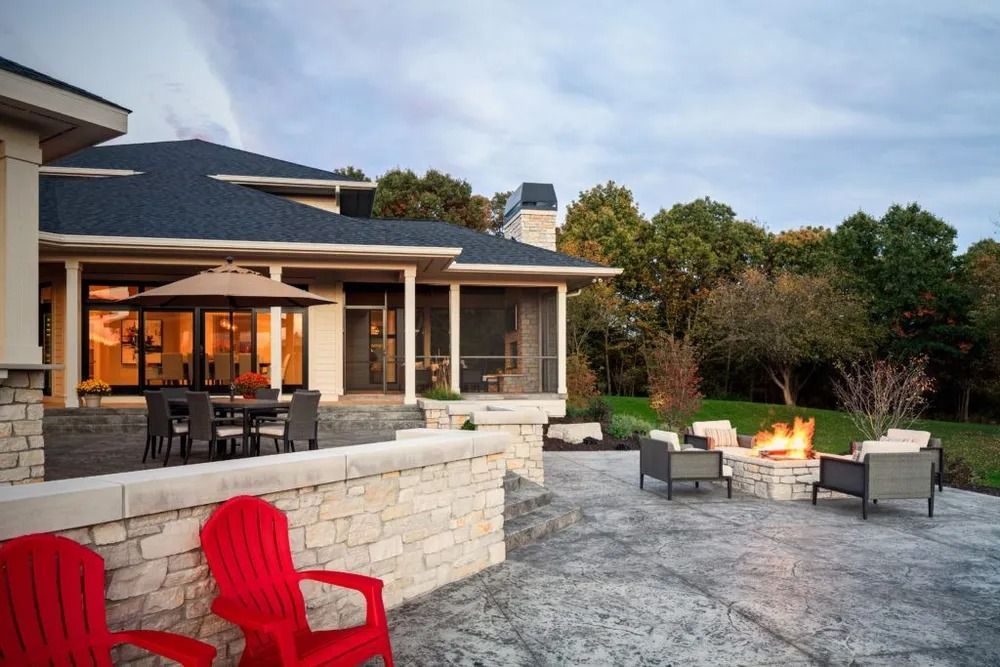 Outdoor patio with stone wall, dining area, fire pit, and house in background.