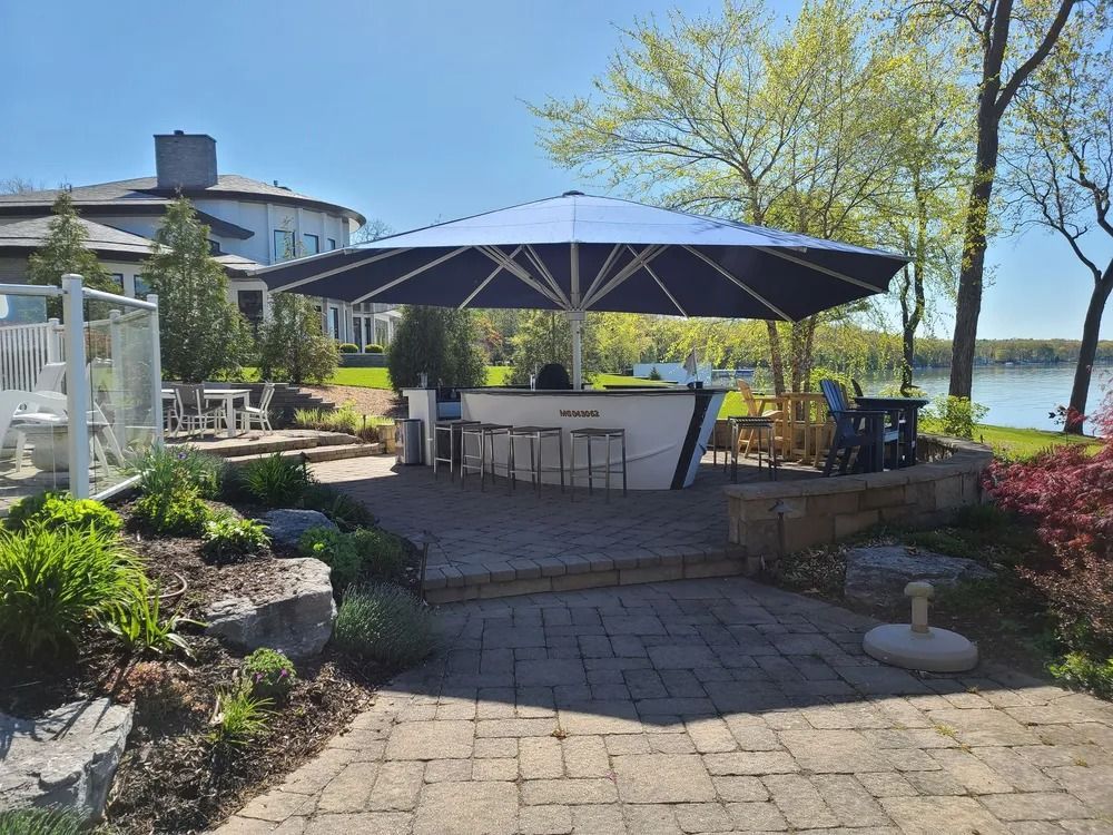 Outdoor bar with blue umbrella, white bar, and waterfront view.
