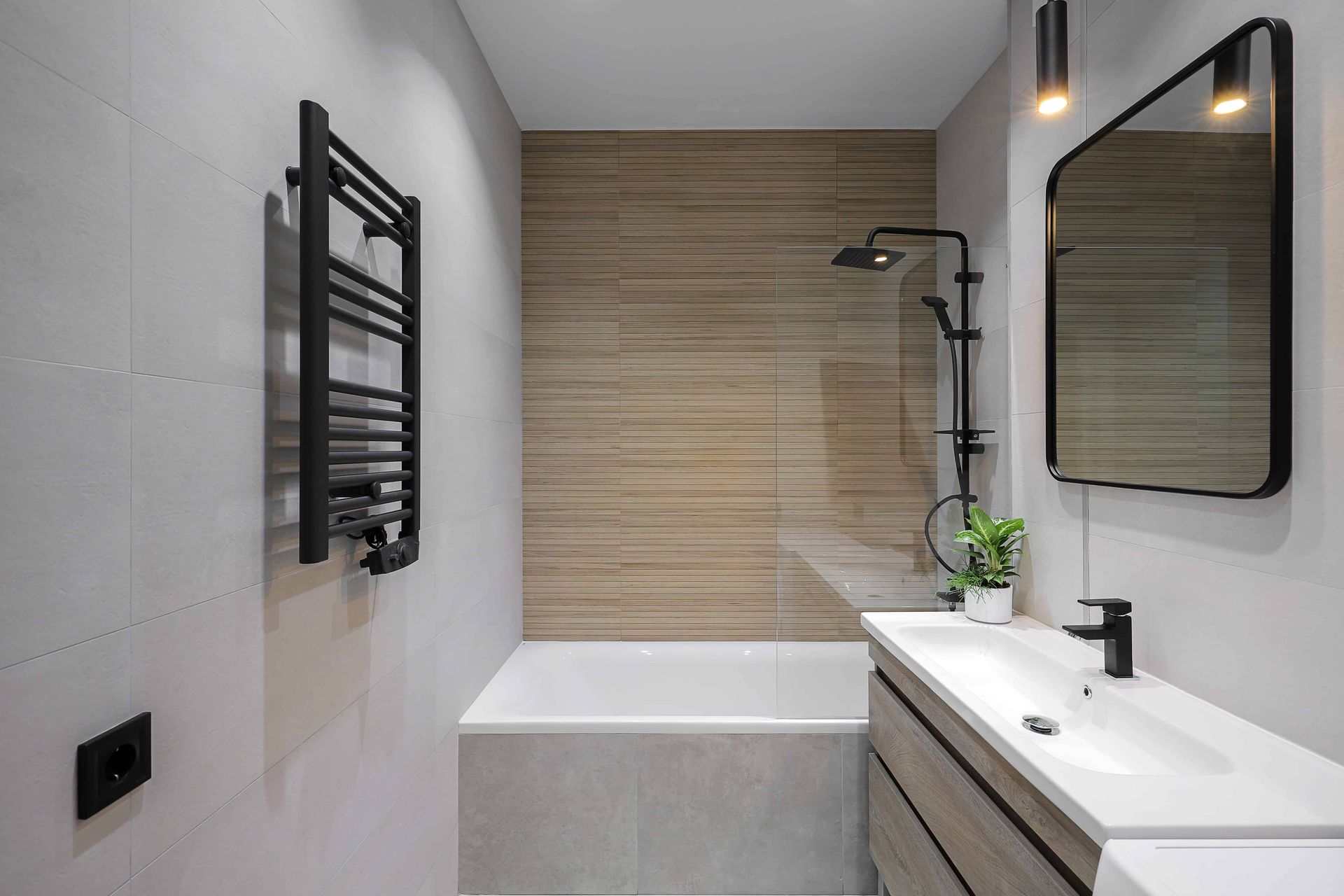 Modern bathroom with a bathtub, shower, vanity, and black towel rack. Neutral colors and sleek design.