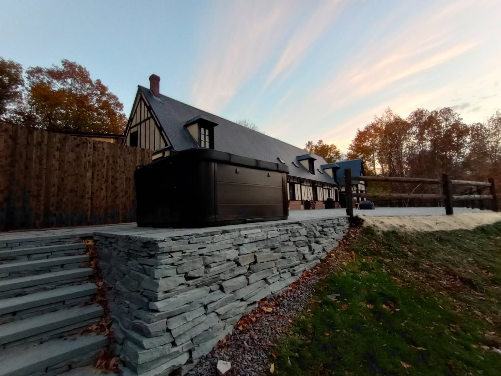 A stone-walled landscape with steps leading to a dark building. Sky is visible behind it.