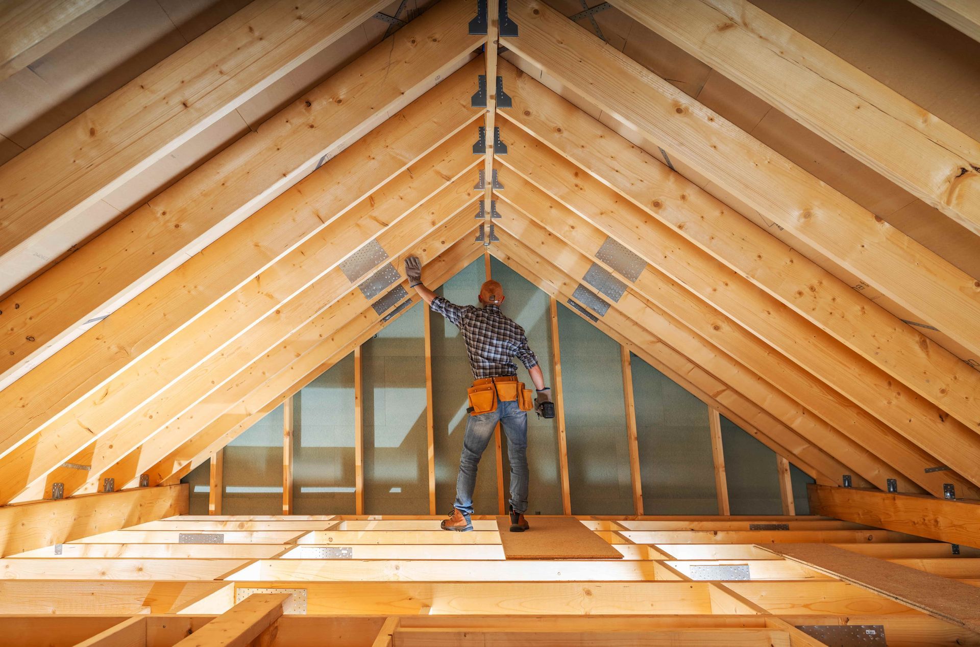 Man inside attic, inspecting wooden beams during construction.