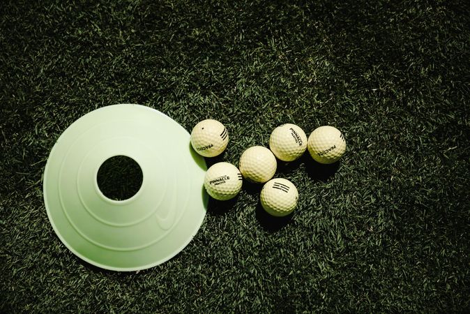A bunch of golf balls and a cone on the ground
