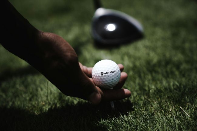 A person is putting a golf ball on a tee.