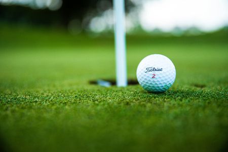 A golf ball is sitting on top of a green near a hole.