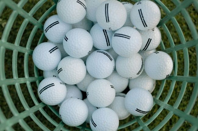 A bunch of golf balls in a green basket