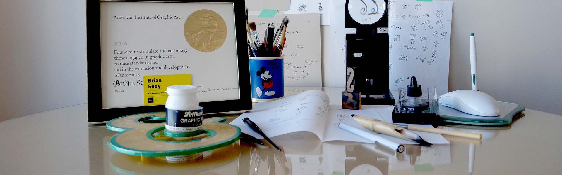 A desk with a picture frame , pens , and a mouse on it