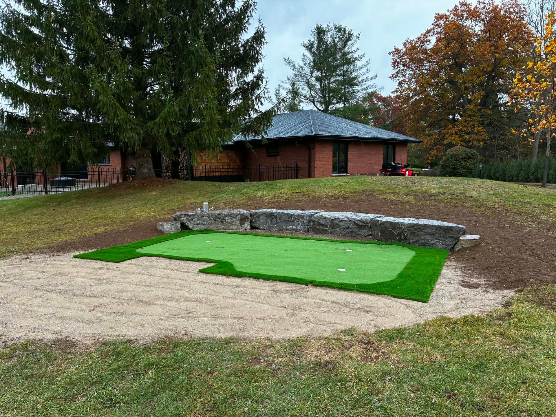 Mini golf putting green with sand trap and stone border in a park setting