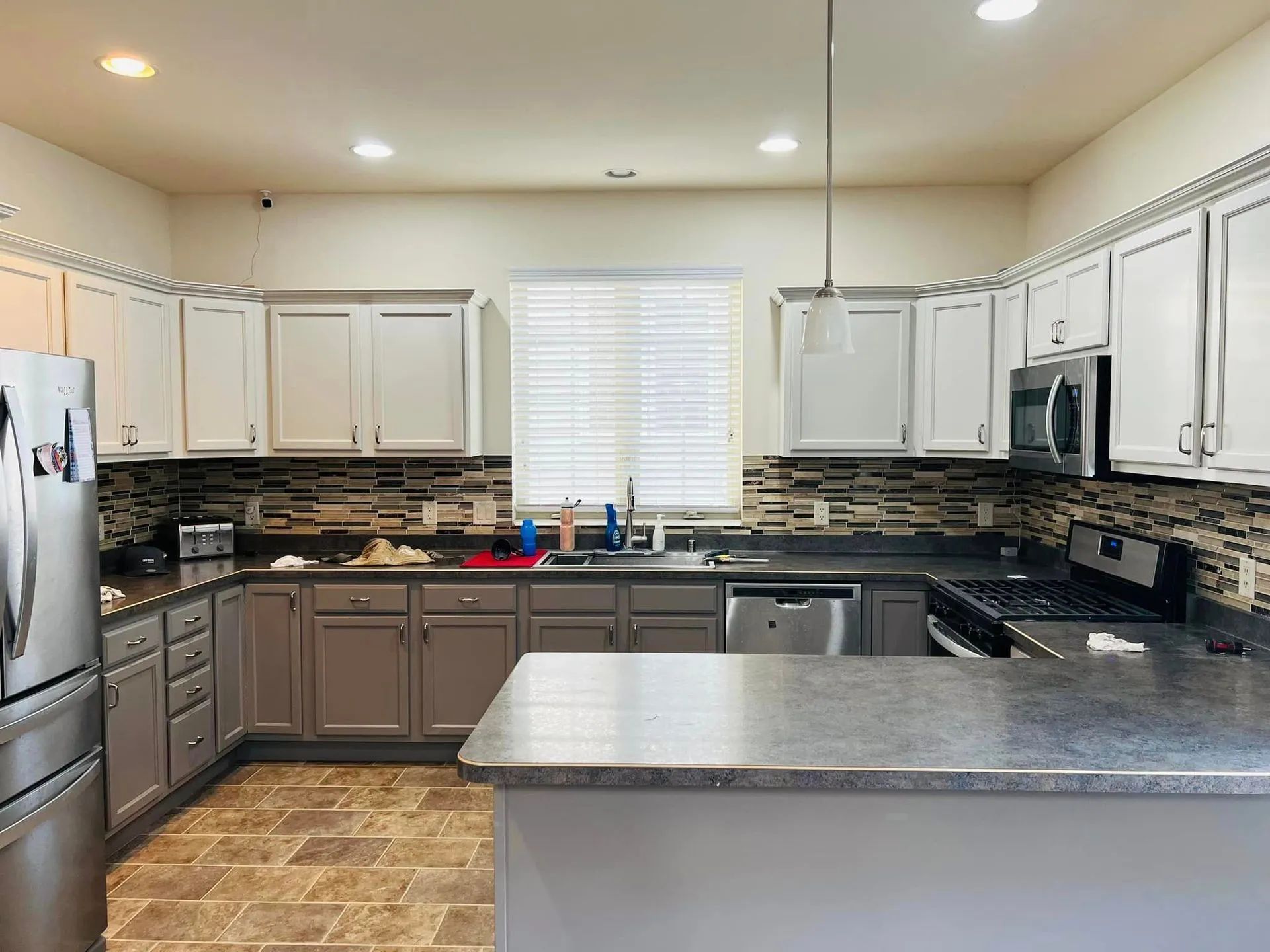Kitchen with gray and white cabinets, stainless steel appliances, and a tiled backsplash.