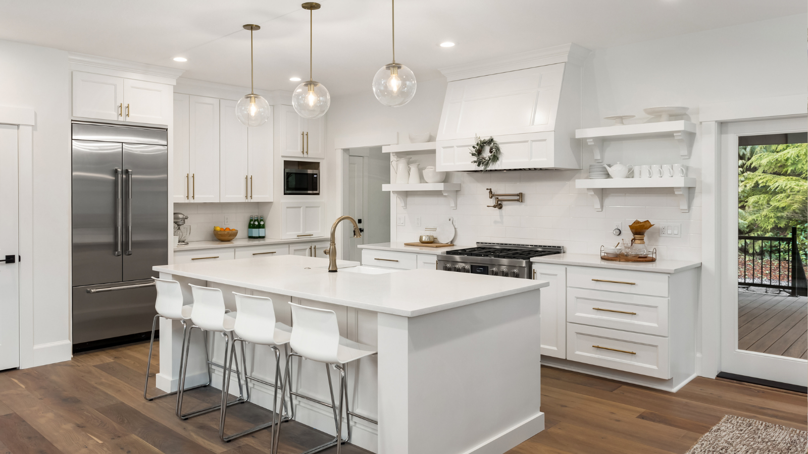 White modern kitchen with island, stainless steel appliances, and wooden floor.