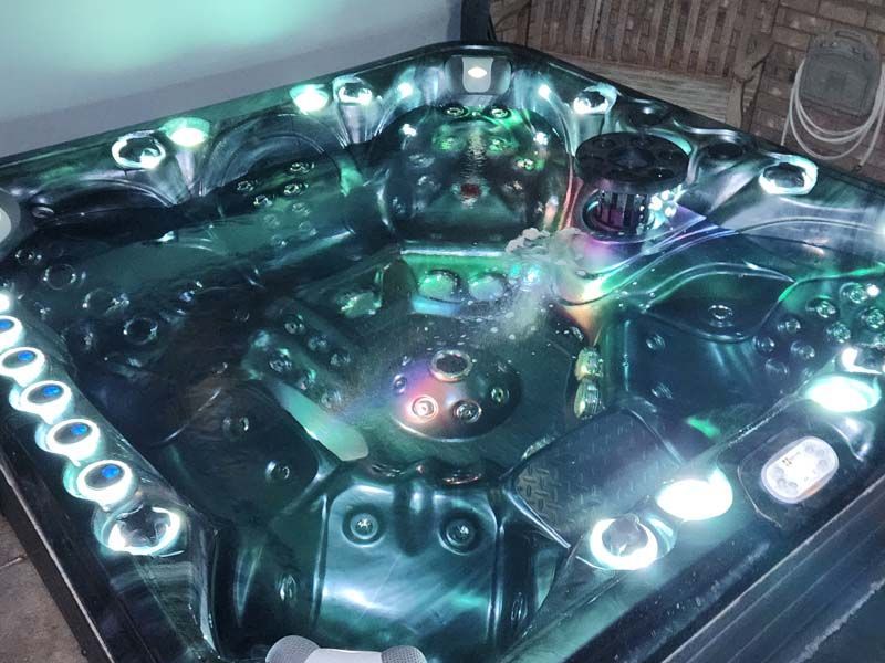 Hot tub with blue and green lights, bubbling water, and a dark interior.