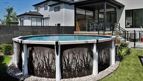 Above-ground pool in a backyard, featuring dark panel design, surrounded by landscaping.