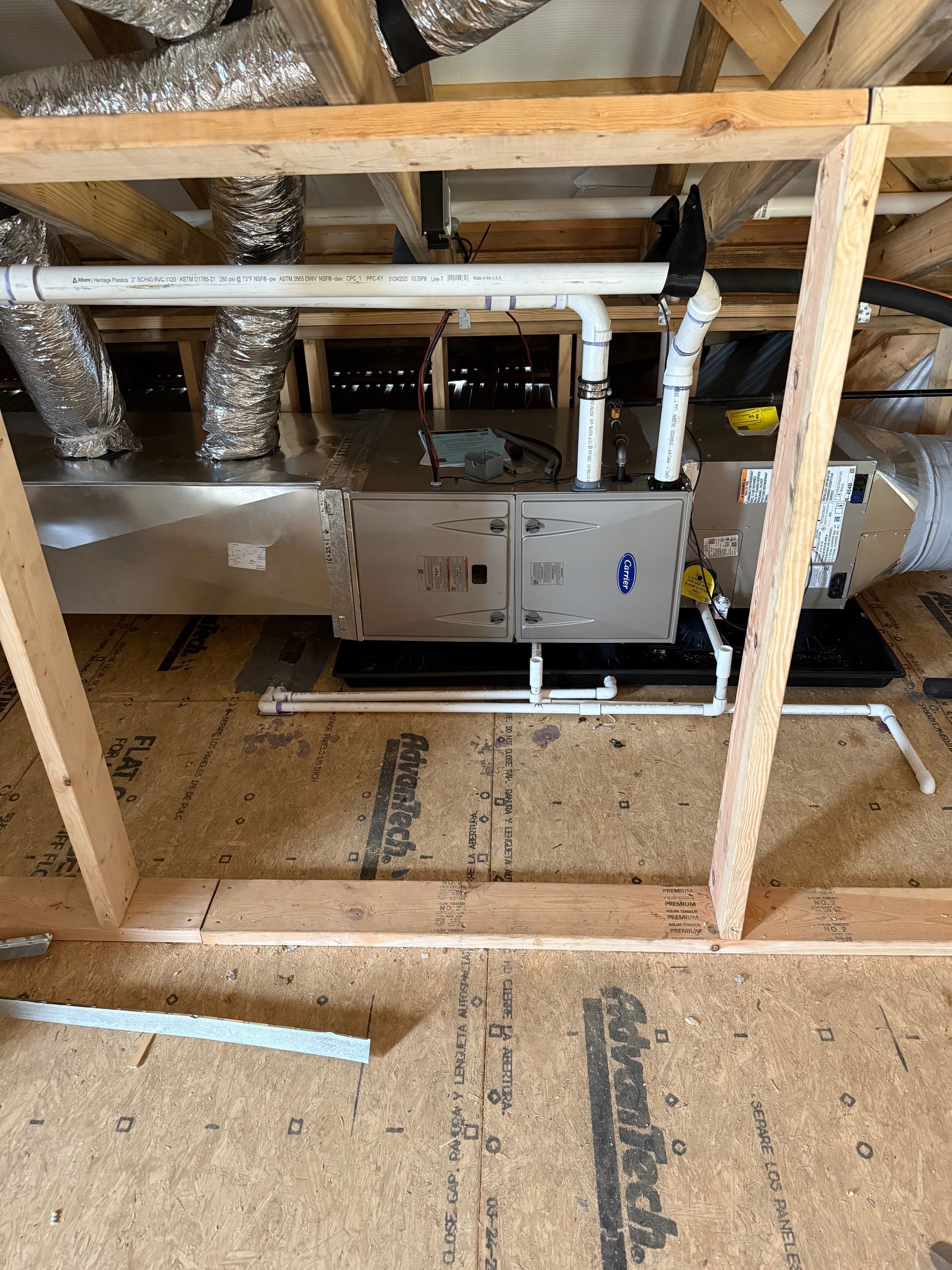 HVAC unit in an attic with ductwork, water pipes, and wooden framing.