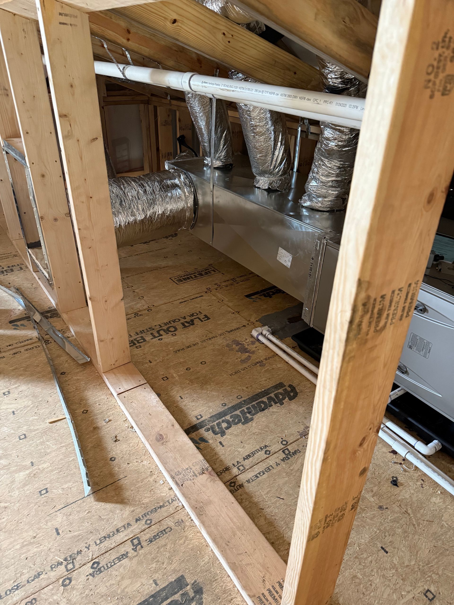 Attic with HVAC system, ductwork, and wooden frame. Light brown wood, silver ducting, and tan flooring.