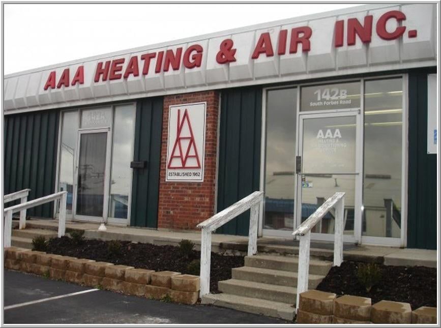 AAA Heating & Air Inc. storefront with red sign, green siding, brick accents, and a small set of stairs.