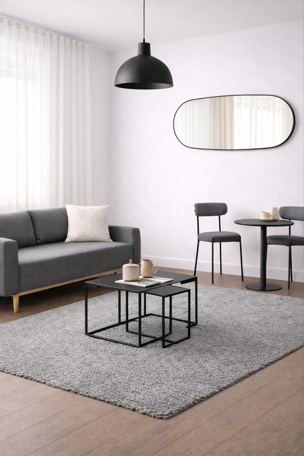 Salon moderne avec canapé gris, tapis et meubles d'appoint noirs.