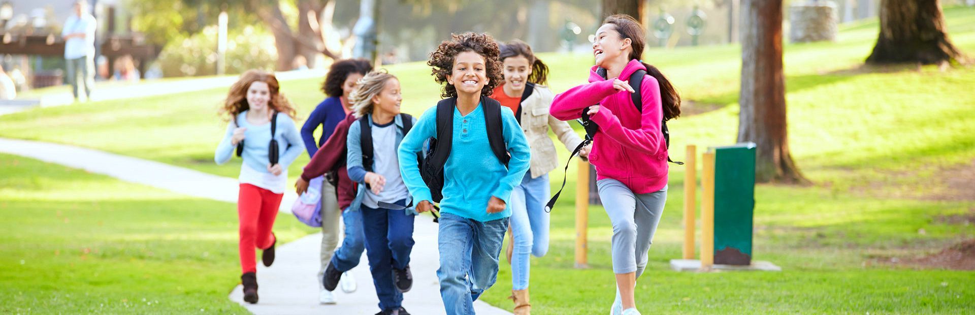 A group of children are running down a path in a park.