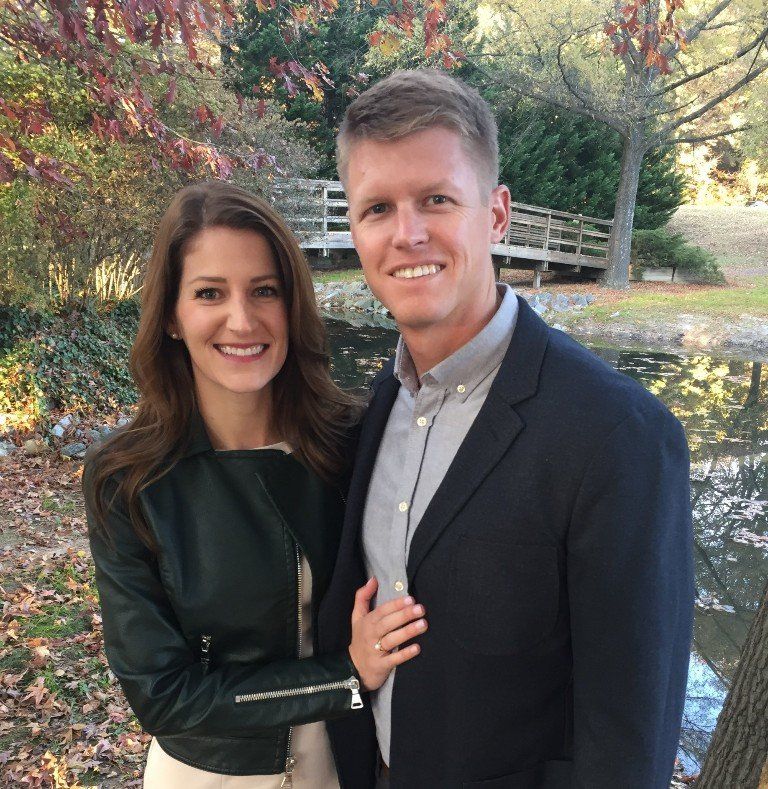 A man in a suit and a woman in a leather jacket are posing for a picture
