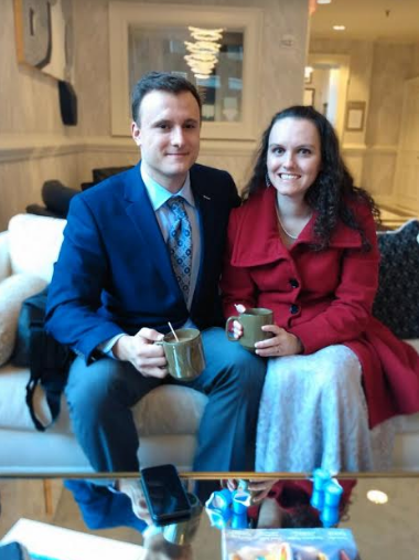 A man and a woman are sitting on a couch holding cups of coffee