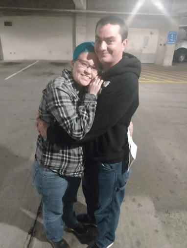 A man and a woman are hugging in a parking garage.