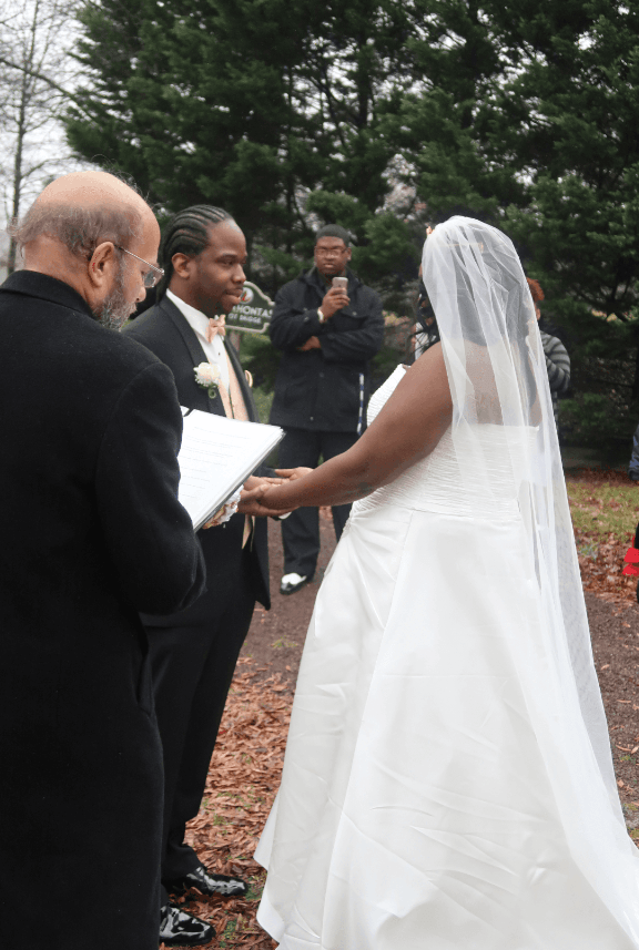 A bride and groom hold hands during their wedding ceremony