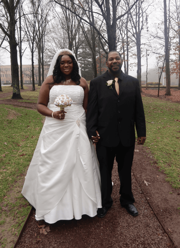 A bride and groom pose for a picture in a park