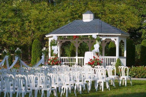 A white gazebo with white chairs in front of it
