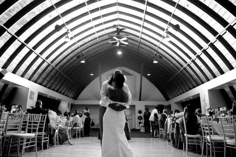 A black and white photo of a bride and groom dancing at a wedding reception.