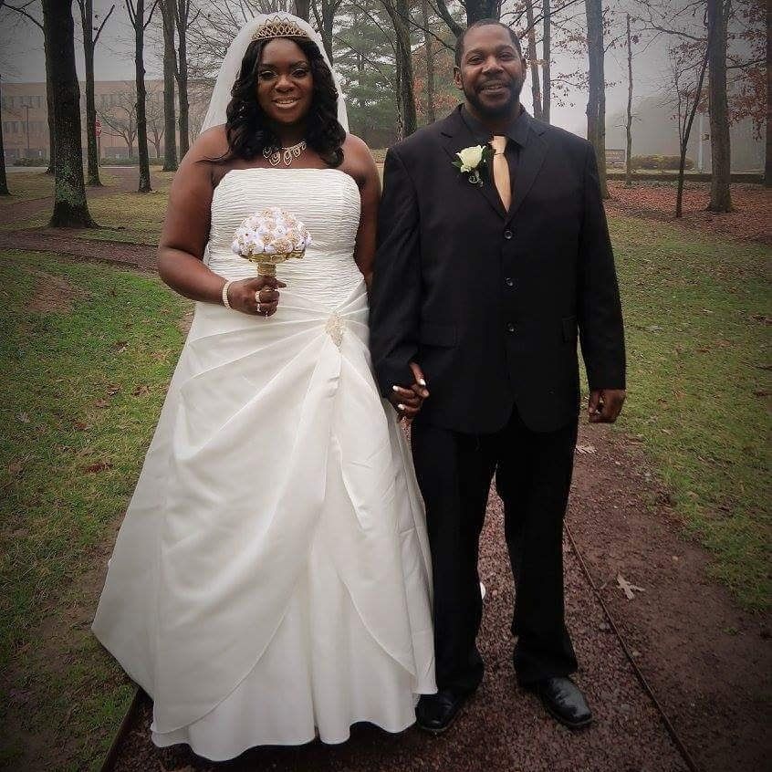 A bride and groom pose for a picture in a park