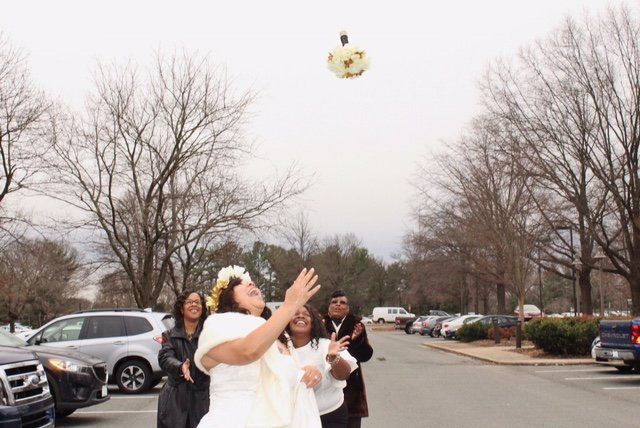 A woman in a white dress is throwing a flower in the air.