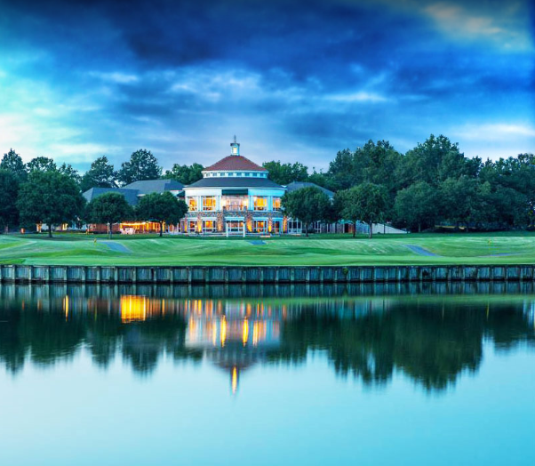 A large house is reflected in the water of a lake.