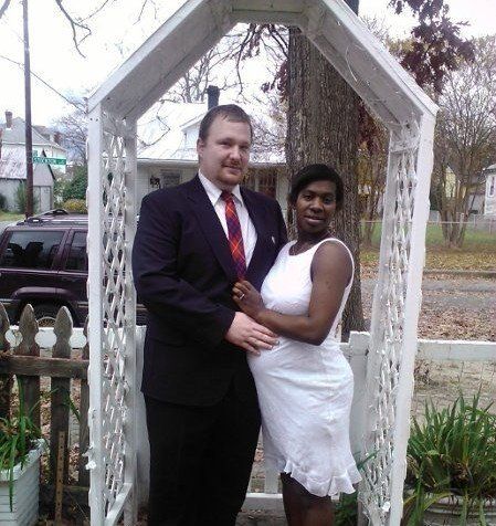 A man in a suit and tie stands next to a woman in a white dress