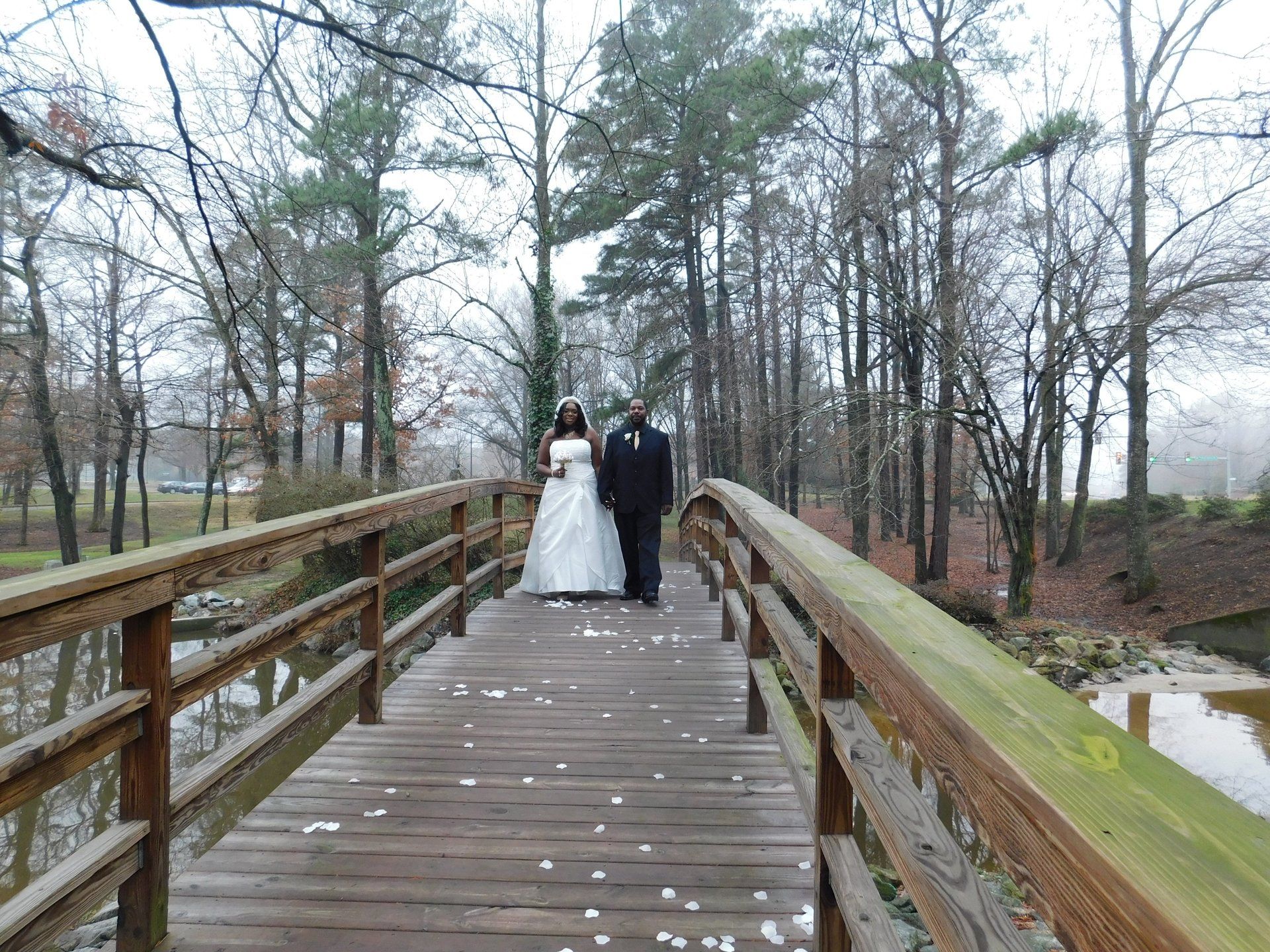 A bride and groom are standing on a wooden bridge.