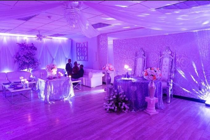 A room with purple lights on the walls and tables and chairs.