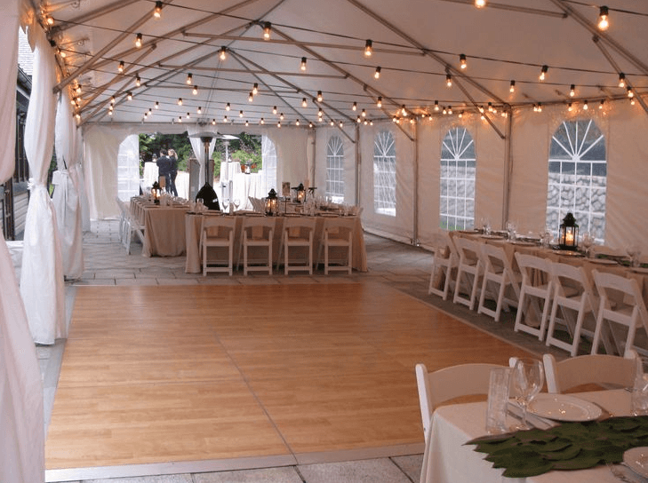 A large tent with tables and chairs and a dance floor