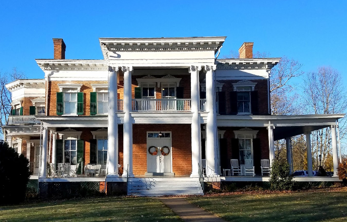 A large brick house with white columns and green shutters