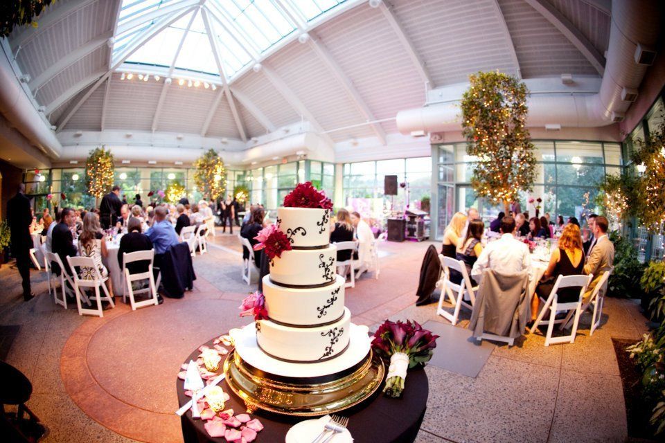 A wedding cake is on a table in a large room