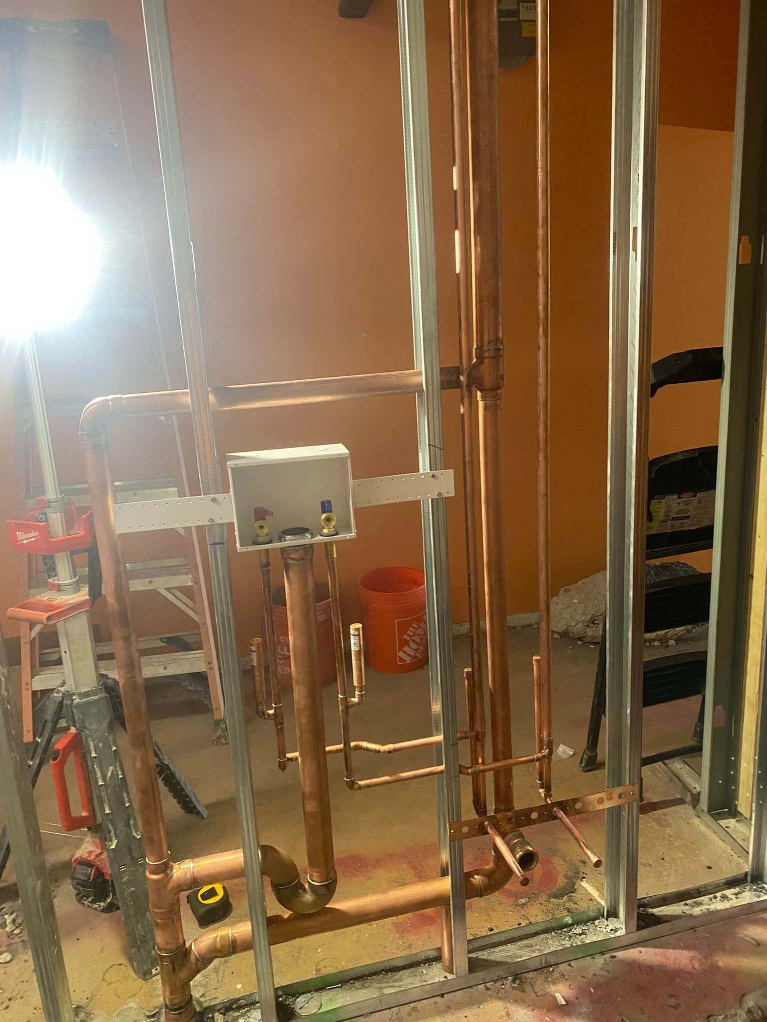 A room with copper pipes and a ladder in it.