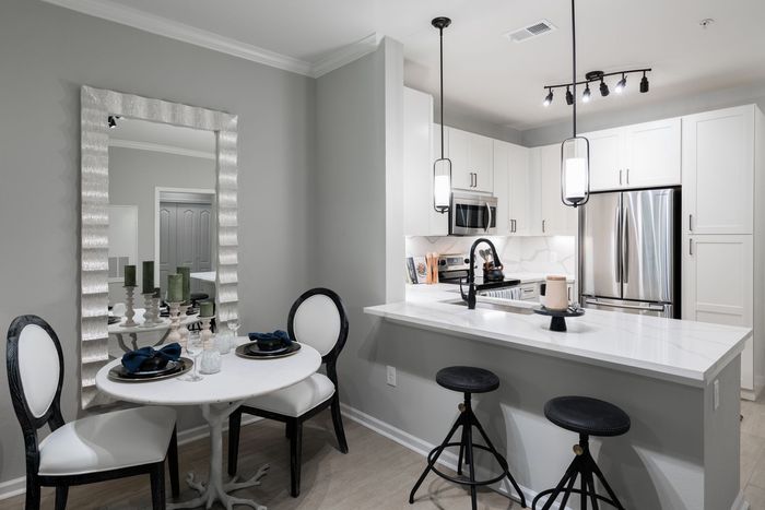 Kitchen with white cabinets, a breakfast bar, and a dining table with ornate chairs.