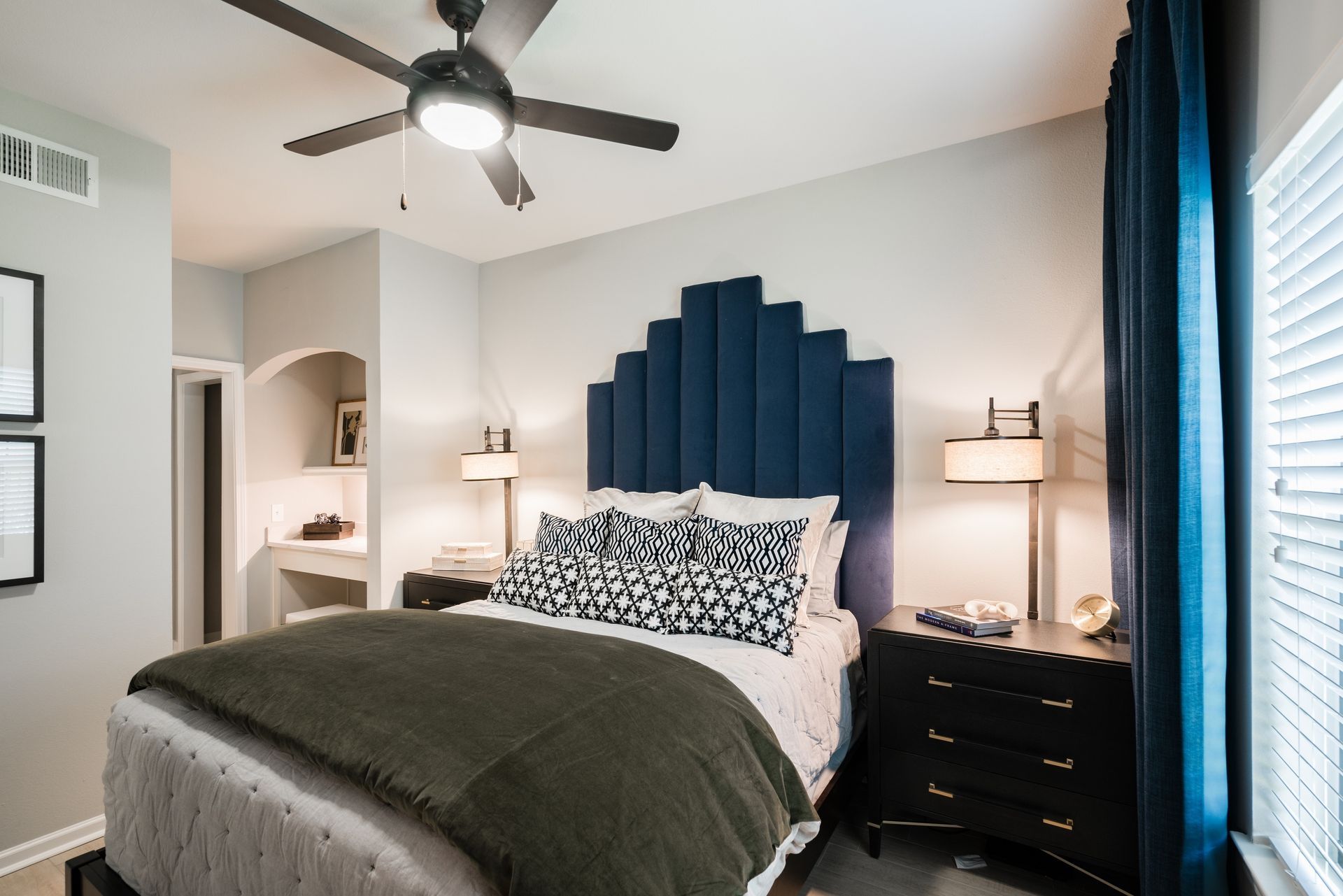 Bedroom with blue headboard, dark furniture, and green blanket.