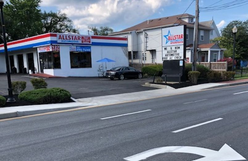 An Allstar Automotive service center building and parking lot, with a roadside sign, next to a street in a suburban area. | Allstar Automotive