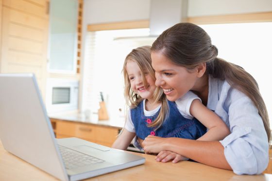 woman with her daughter working on laptop