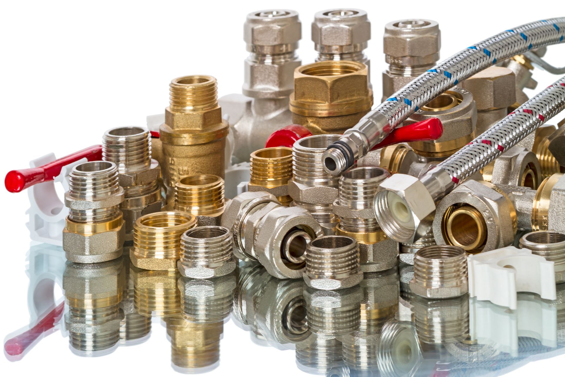 Assorted brass and metal plumbing fittings, valves, and flexible hoses arranged on a surface. Assorted brass and metal plumbing fittings, valves, and flexible hoses arranged on a surface.