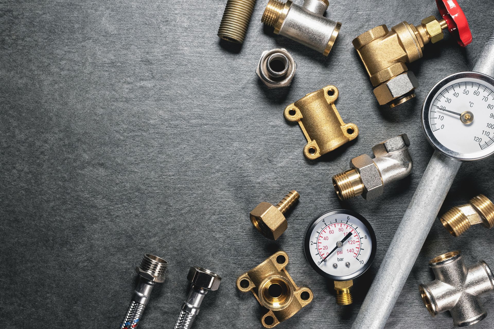 Plumbing parts and equipment lay on a gray, flat background.
