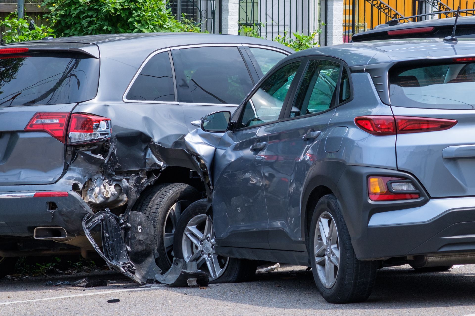 Two damaged gray SUVs after a collision, impact visible on the rear of one and the side of the other.